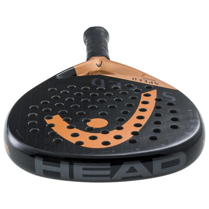 A close-up of the HEAD Speed Motion 2023 Padel Racket by HEAD, showcasing its Auxetic technology, black and orange perforated face, "HEAD" and "SPEED" logos, and a black grip handle.