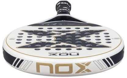 A close-up of the NOX Equation Advance Series Padel Racket for intermediate players, showing its rounded face with circular holes, black and gold design, NOX logo, and black grip tape on the handle.