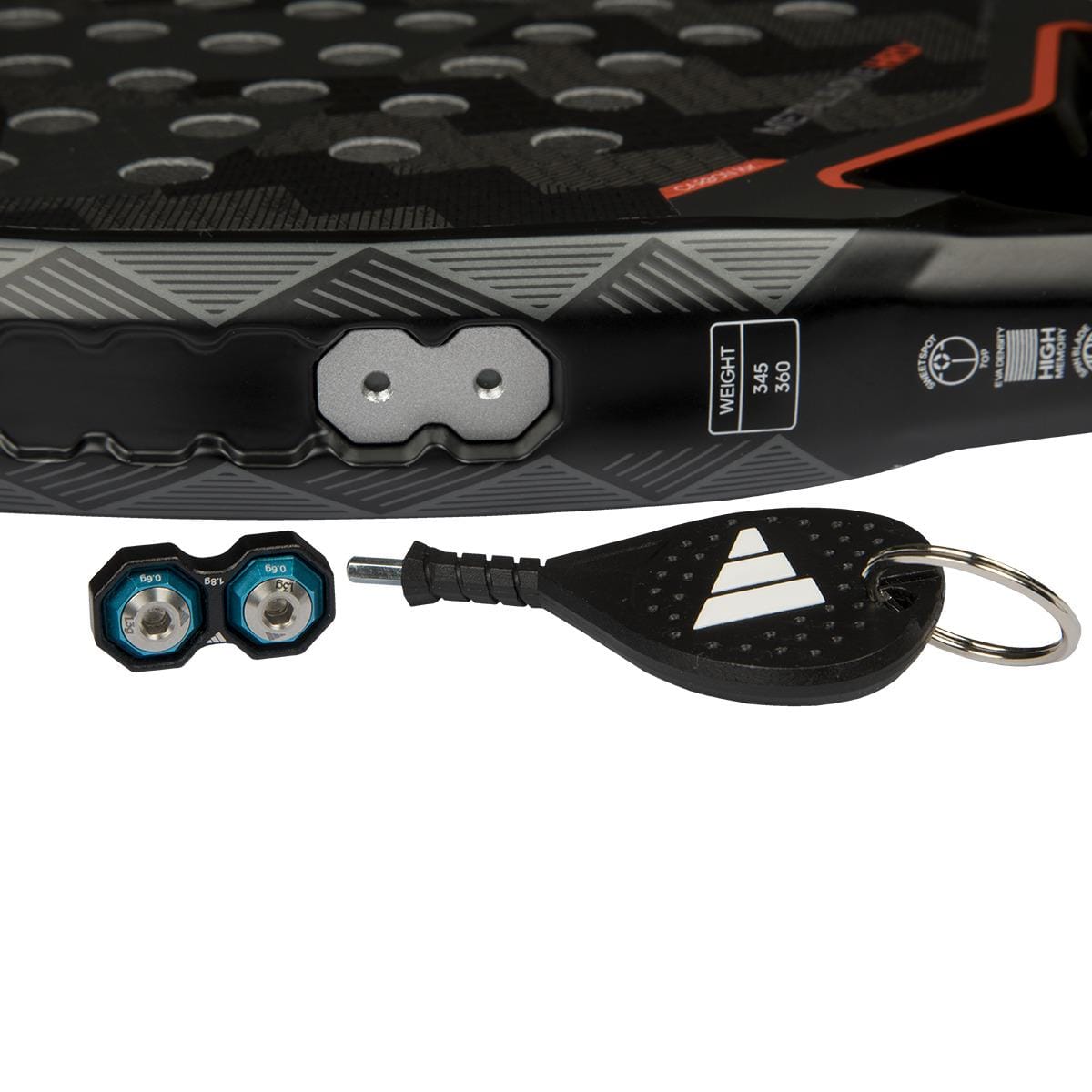 Close-up of the adidas Metalbone 3.4 Padel Racket displays its weight label, two small blue weights, and a black keychain tool with a white logo on a white surface.