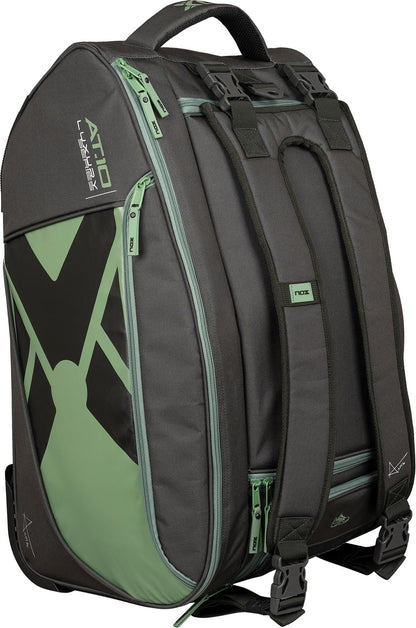The NOX AT10 Competition Trolley Padel Racket Bag in black and green features geometric accents, multiple zippers, sturdy handles, adjustable straps, and wheels. This NOX bag stands upright on a white background.