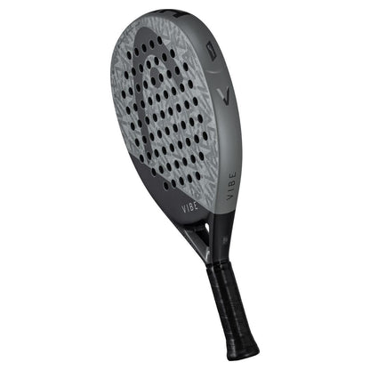 The HEAD Vibe 2025 Grey / Black Padel Racket from HEAD features a textured, round face with multiple holes, "VIBE" printed near the handle, and a black grip.