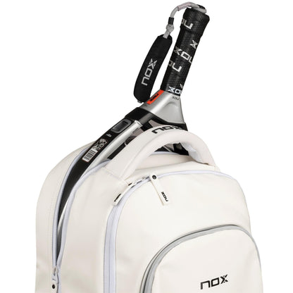 A close-up of the NOX Pro Series Padel Backpack - White by NOX shows its curved seams, front pocket with NOX logo, and a partially open zipper revealing a padel racket handle inside the main compartment.