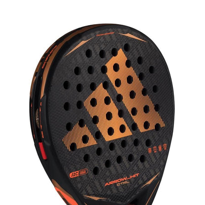 Close-up of the adidas Arrow Hit CTRL 2026 Padel Racket with an orange geometric design, round holes, "ARROW-HIT" and "STEEL" text, and an intelligent balance system for precise court control.
