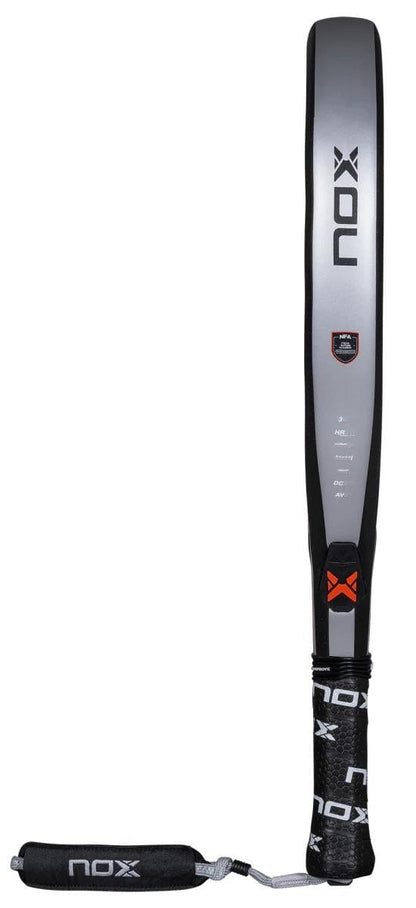 The NOX NFA Nextgen Pro Attack 3K padel racket, in gray and black, is displayed upright with the NOX logo, a wrist strap, and a handle featuring the brand name—an ideal high-performance choice.
