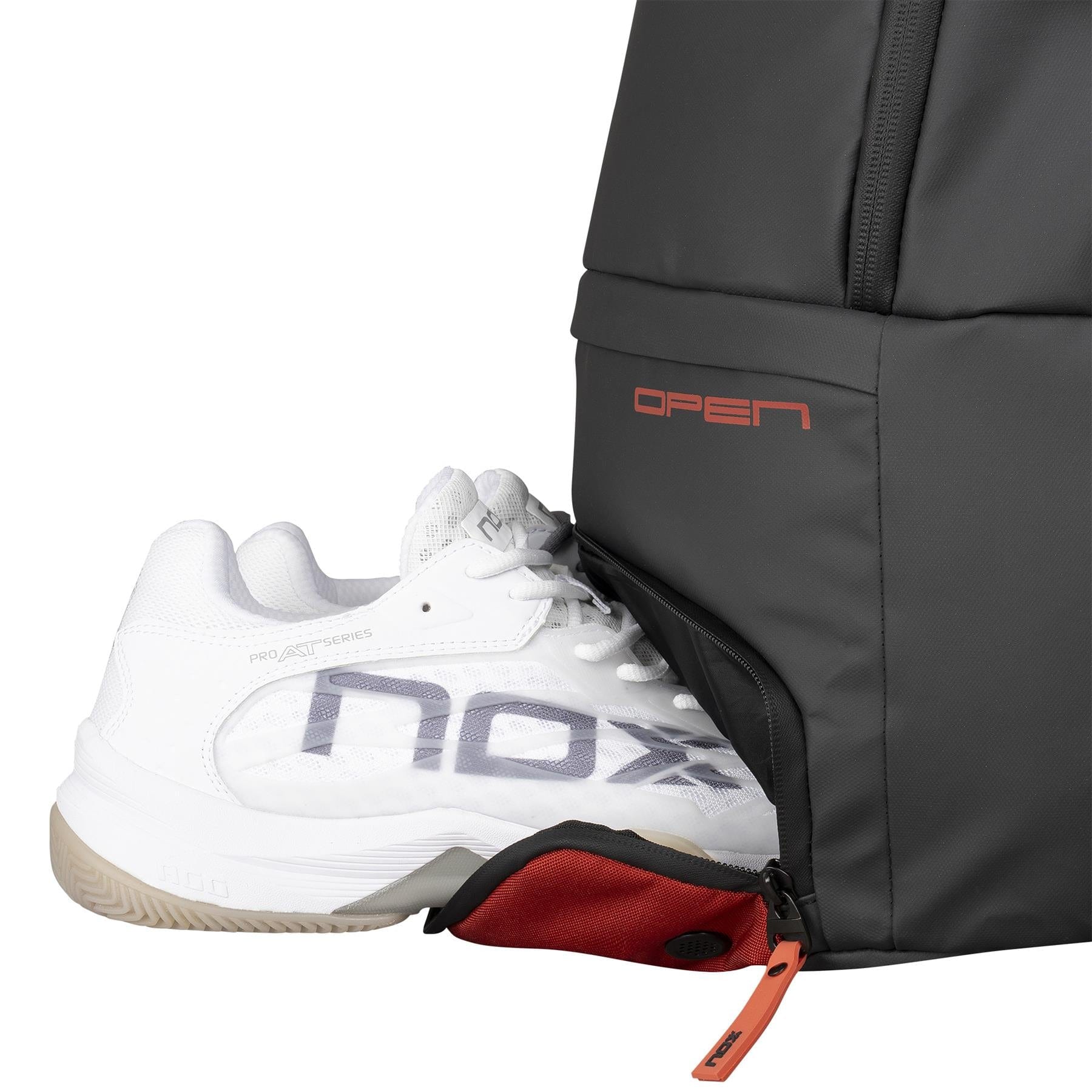 A white sports shoe with "nox" on its side and a beige sole is partly pulled from the NOX Luxury Open Series Padel Backpack - Black / Red, crafted from technical materials and detailed with "OPEN" in bold red letters.