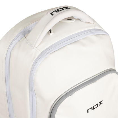 Close-up of the NOX Pro Series Padel Backpack - White by NOX, featuring light gray zippers and trim plus "nox" in black on the handle and front pocket—a stylish choice for padel players on the go.