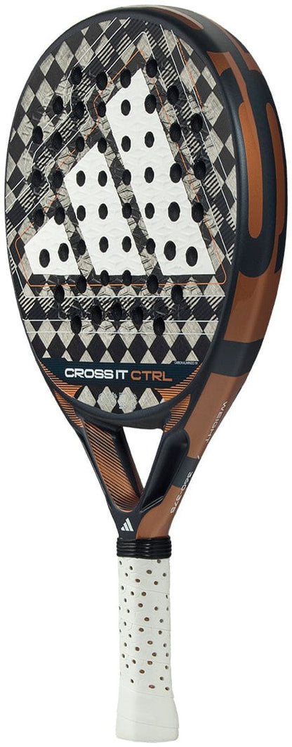 A close-up of the adidas Cross It Ctrl 2026 Padel Racket highlights its geometric black, brown, and white design, circular holes, white grip handle, and “CROSS IT CTRL” text. Made from carbon fibre, it features advanced Spin Blade Mould technology.