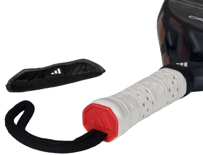 Close-up of the adidas Cross It Ctrl 2026 Padel Racket handle, featuring a white grip, red end cap, and black wrist strap. A black protective cover with a white logo lies nearby, showcasing the carbon fibre racket’s premium quality.