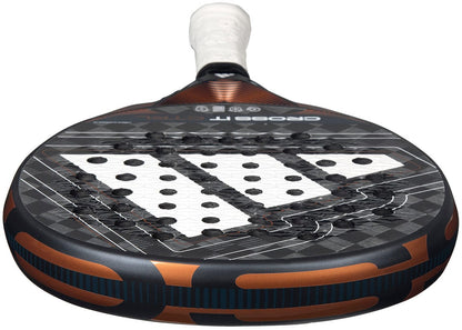 A close-up of the adidas Cross It Ctrl 2026 Padel Racket, a carbon fibre padel racket in black, white, and copper with visible holes, a white grip, and Spin Blade Mould technology.