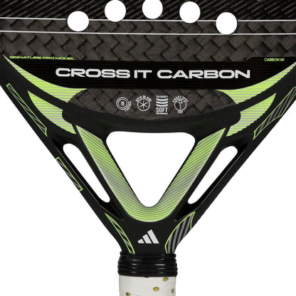 Close-up of the throat of the adidas Cross It Carbon 2026 padel racket, featuring white text, circular cutouts, a carbon fiber pattern, and the adidas logo near the handle.