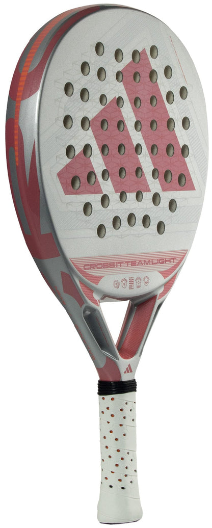 The adidas Cross It Team Light 2026 Padel Racket features a white and pink design, circular face holes, a textured Extra Power Grip, lightweight build, and prominent adidas logo.