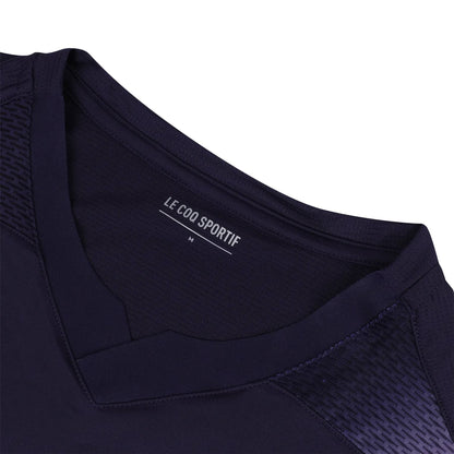Close-up of a deep purple V-neck padel t-shirt featuring a textured shoulder pattern, showcasing the "Le Coq Sportif" label and size "M" inside the collar. Designed for movement and breathability, this Le Coq Sportif Pro Men's Padel T-Shirt is perfect for your active lifestyle.
