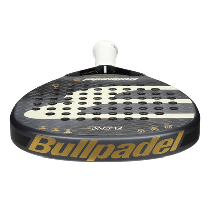 A close-up of the Bullpadel Flow Legend 2026 Padel Racket shows its black face, white handle, circular holes, and bold gold "Bullpadel" branding—featuring Flowforce tech tailored for women.