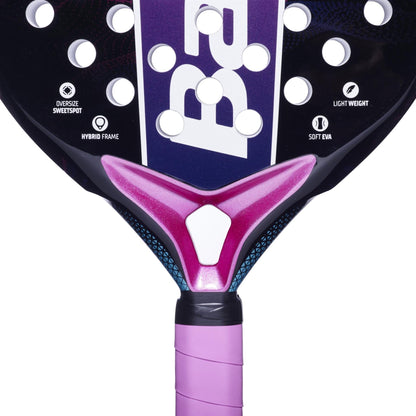 Close-up of the Babolat Stima Vita Padel Racket, a lightweight model with a purple and black design and pink grip. Icons highlight its beginner-friendly features: oversized sweet spot, hybrid frame, soft EVA. Partially visible bold white Babolat branding.
