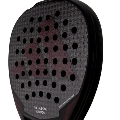 Close-up of the adidas Metalbone Carbon 3.3 padel racket in black, featuring a honeycomb texture, circular holes, and "METALBONE CARBON" plus "STRUCTURAL REINFORCEMENT" near the bottom—ideal for advanced players.