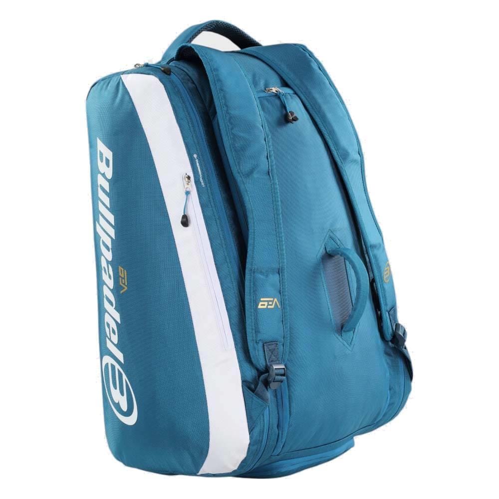 The Bullpadel BPP26021 Pearl Padel Racket Bag in blue features white accents, multiple zippered compartments, handles, and shoulder straps for easy carrying. The Bullpadel logo is prominently printed on the side.