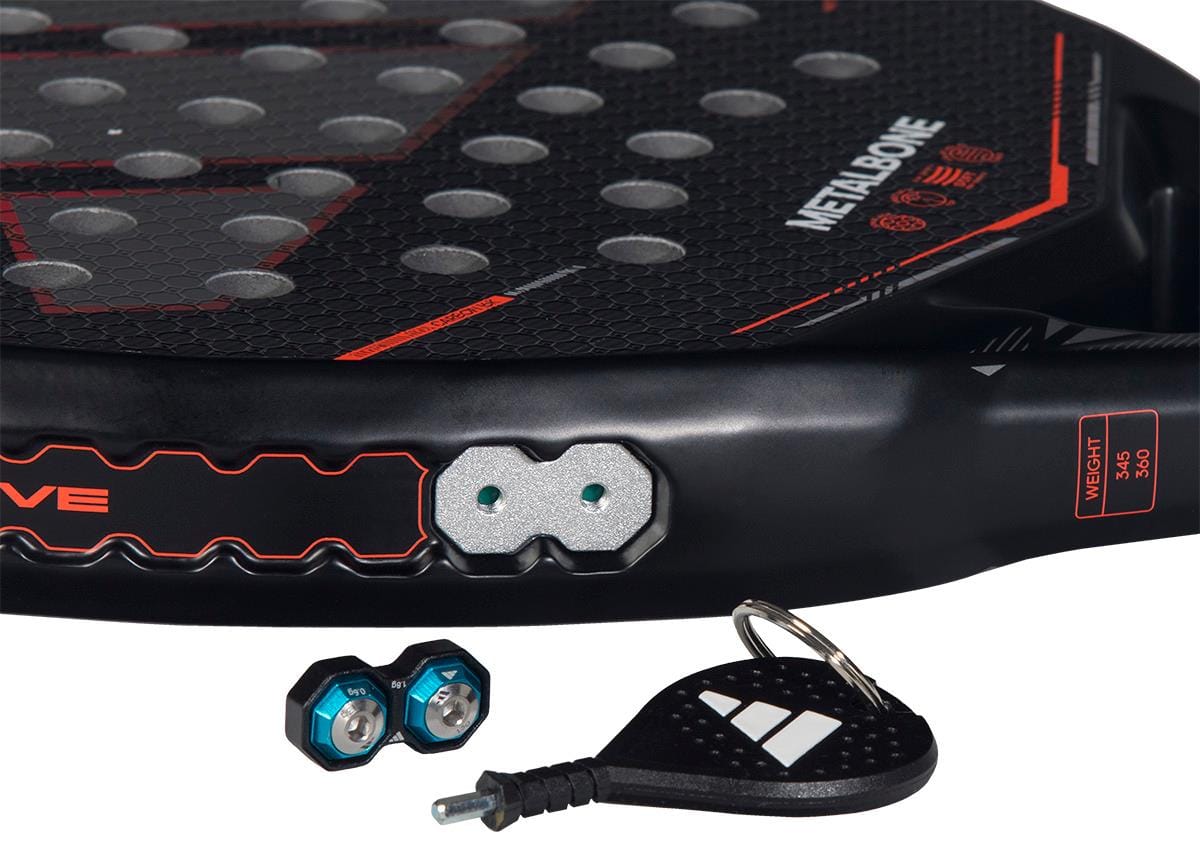 Close-up of the adidas Metalbone by Ale Galán 2026 Padel Racket, showing the "METALBONE" label, weight and balance system with two hexagonal weights, adjustment screws, and a small black adidas key tool with keyring nearby.