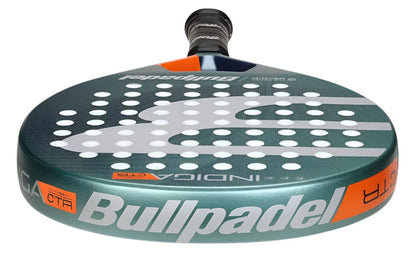 Close-up of the Bullpadel Indiga Ctr 2025 Padel Racket, featuring a circular perforated face, green and orange details, bold Bullpadel logo, textured surface, and handle positioned away.