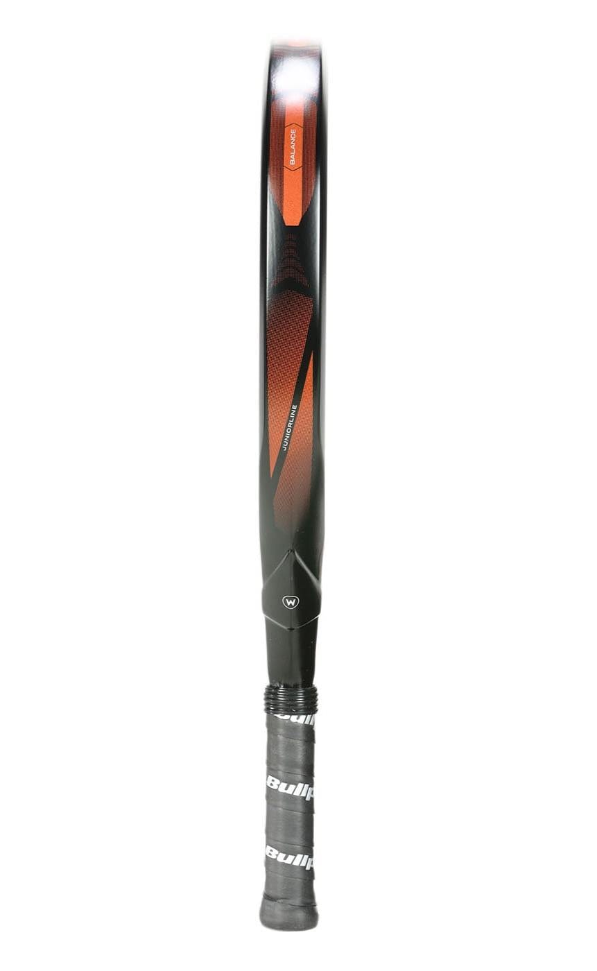 A black and orange Bullpadel Vertex Junior 25 padel racket stands vertically, handle down, featuring a diamond-shaped head and a black grip with Bullpadel branding, similar to designs found in junior padel racket models.