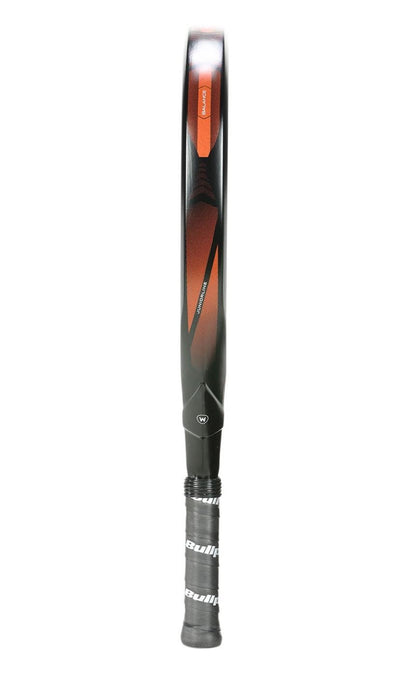 A black and orange Bullpadel Vertex Junior 25 padel racket stands vertically, handle down, featuring a diamond-shaped head and a black grip with Bullpadel branding, similar to designs found in junior padel racket models.