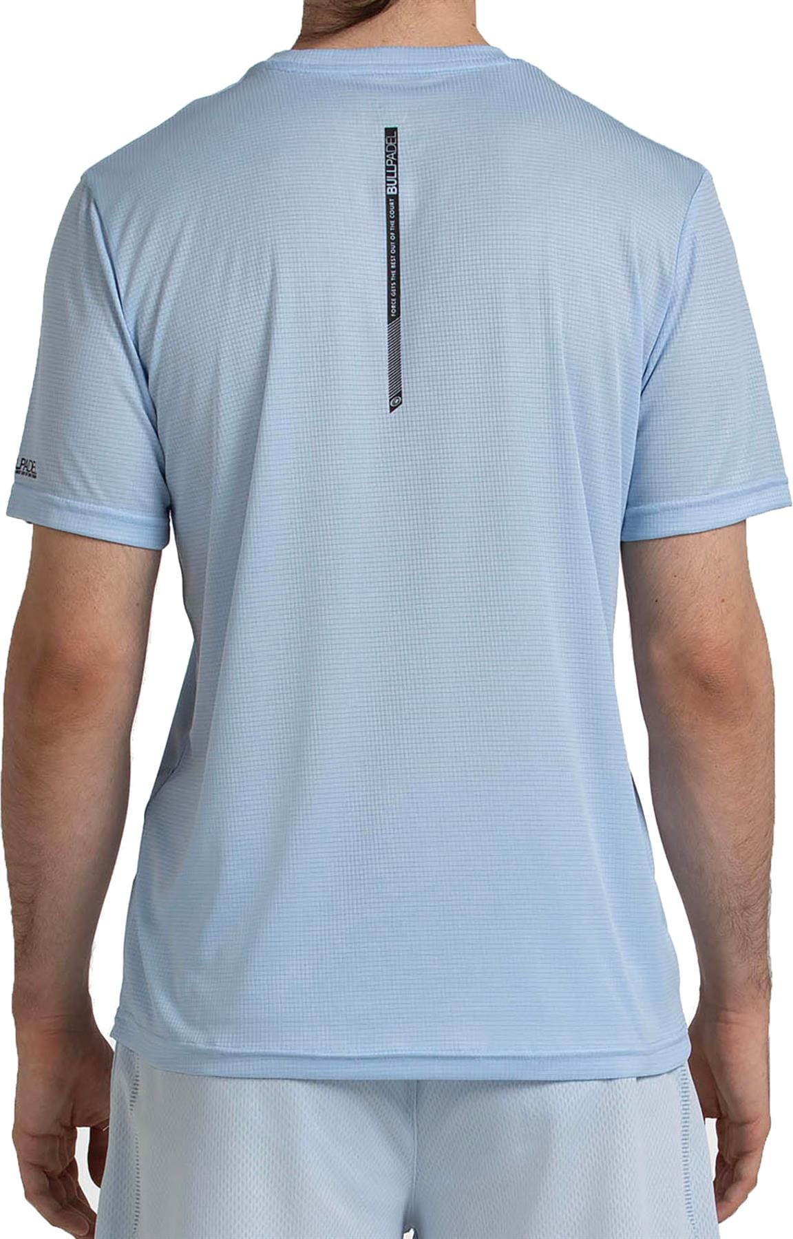 A man is seen from the back wearing the Bullpadel Casinas Men's Padel T-Shirt in Glacier Blue, made from lightweight polyester with Quickerdry technology. The shirt features a small black tag with vertical text near the upper back.