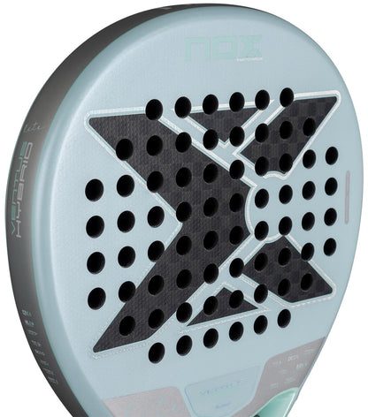 Close-up of a NOX Luxury Ventus 12K Hybrid Lite 2026 padel racket in light blue, showing a bold black "X," round holes, and surface text like "HYBRID" and "Vermis." The racket features durable 12K carbon fibre.