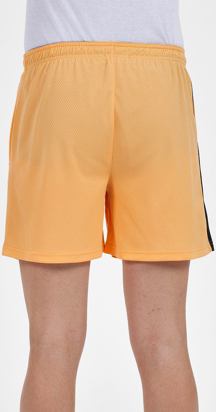 A person seen from the back stands against a plain white background, wearing Bullpadel Campaza Men's Padel Shorts in orange by Bullpadel, featuring a black side stripe.