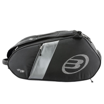 The Bullpadel Neuron 25 Padel Racket Bag in black is ideal for padel rackets. It features a zippered main compartment, an extra small pocket, a circular side logo, and a shoulder strap for easy transport of gear like the Bullpadel Neuron 25 or Flow Padel Racket.