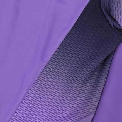 Close-up of a fabric emphasizing its fluidity, showcasing a gradient pattern that transitions from solid purple on the left to a textured black-and-purple on the right. The design is reminiscent of the Le Coq Sportif Pro Mens Padel T-Shirt in Chive Blossom, with small, repetitive lines creating a modern and dynamic appearance.