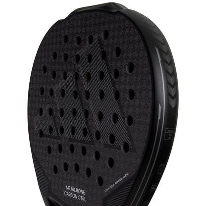 Close-up of an adidas ADIDAS Metalbone Carbon CTRL 3.3 Padel Racket in black, featuring textured surface with circular holes and "METALBONE CARBON CTRL" and "SPIN BLADE." The sleek design highlights the Spin Blade decal on its durable 6K carbon structure.