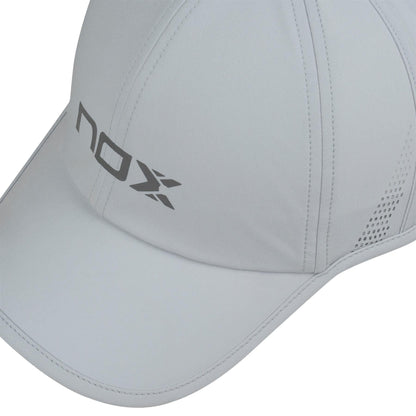 A close-up of the NOX Padel Cap - Grey by NOX, featuring stitched panels, side ventilation holes, and an adjustable velcro strap. "nox" and an "X" logo are printed in gray on the front panel for comfort and sun protection.