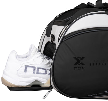 A black and white NOX Luxury Master Series Padel Racket Bag with "nox" branding is shown with a zippered compartment partially open, revealing white athletic shoes similar to those used by Miguel Lamperti.