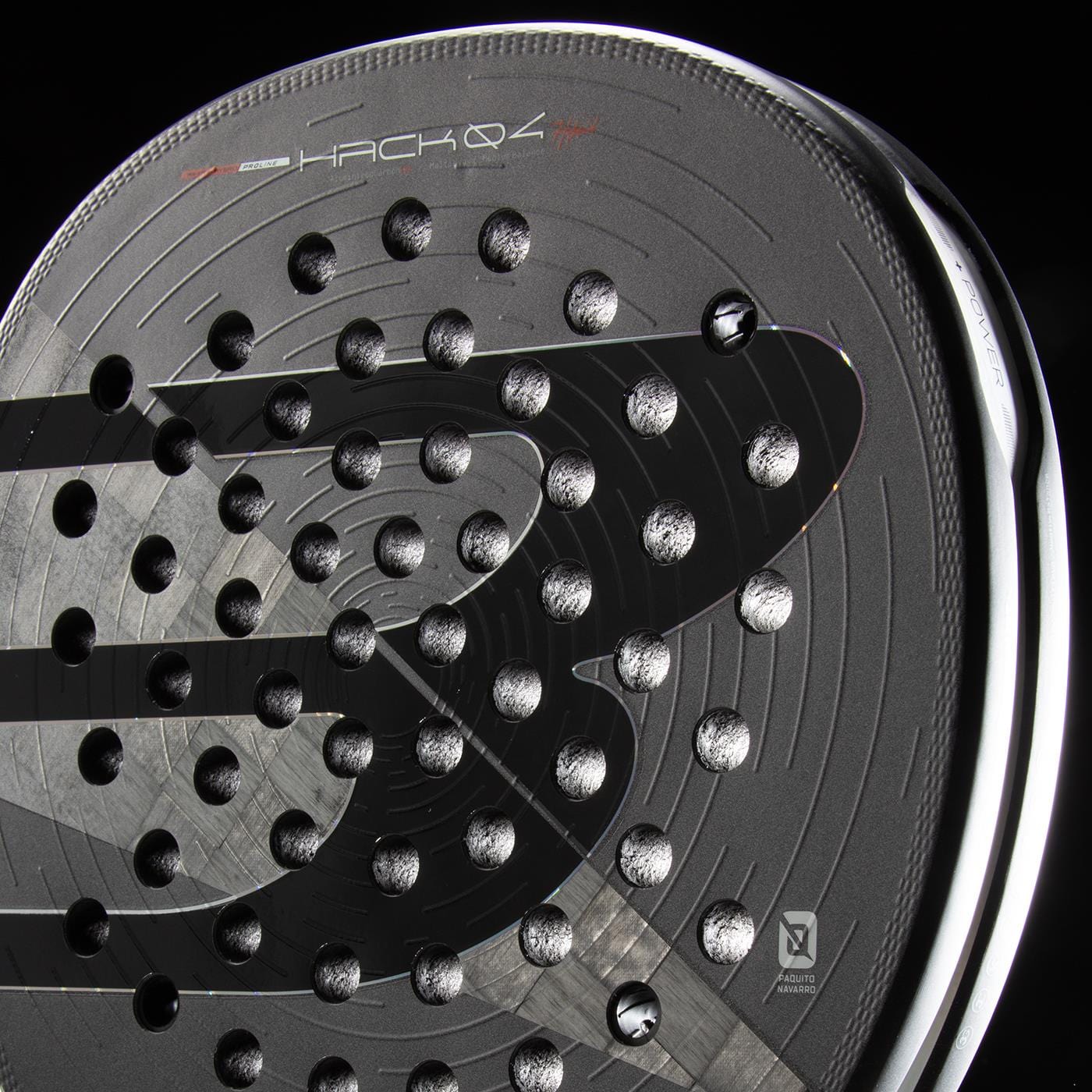 Close-up of the Bullpadel HACK 04 Hybrid 2026 padel racket in black, featuring a modern design with circular perforations, glossy finish, subtle gray stripes, branding details, and advanced Total Channel technology.