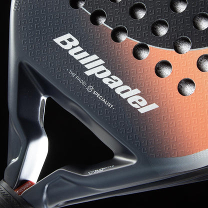Close-up of the Bullpadel Elite W 2026 Padel Racket, a lightweight racket with the Bullpadel brand, textured surface with circular holes, and a stylish black and orange pattern.