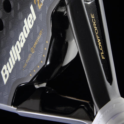 Close-up of the Bullpadel Flow Legend 2026 Padel Racket by Bullpadel, showcasing its logo, textured black and gray surface, gold "THE RADY SPECIALIST" text with stars, and "FLOWFORCE" technology—all against a dark background.