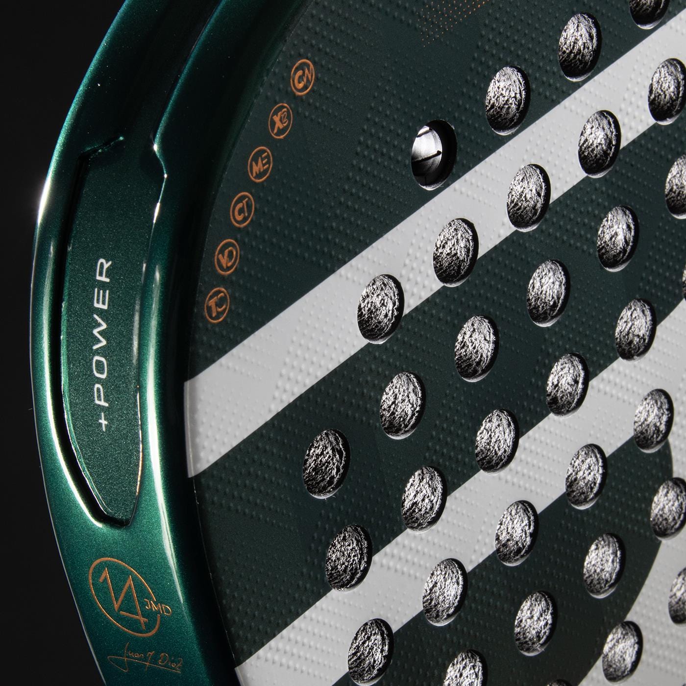 Close-up of the Bullpadel Icon 2026 Padel Racket by Bullpadel, showcasing its green and black design with white diagonal stripes, round holes, "+POWER" and Juan Martín Díaz's signature on the rim, plus small gold icons on the surface.