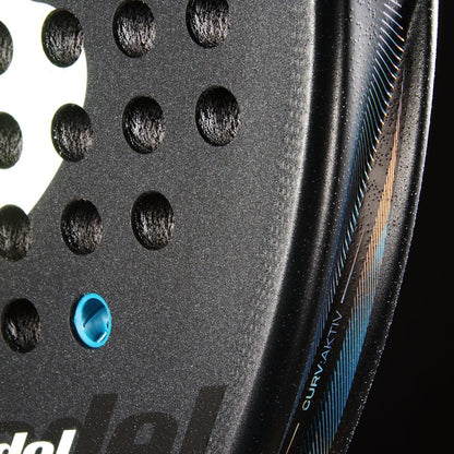Close-up of the Bullpadel Vertex 05 Comfort 2026 Padel Racket in black, featuring textured holes, blue accents, "CURV AKTIV" on the edge, visible Fibrix fibre construction, and part of a white Bullpadel logo on the left.