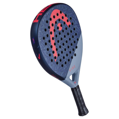 A close-up of the HEAD Vibe 2025 Blue / Red Padel Racket shows its oversized teardrop shape, blue and gray colors, bold red HEAD logo, black grip, multiple holes on the face, and “VIBE” printed near the handle.