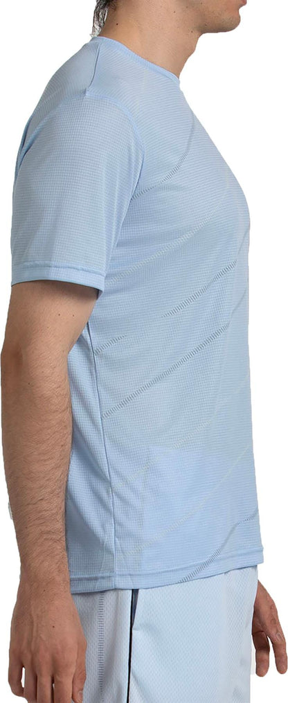 A man in profile wears the Bullpadel Casinas Mens Padel T-Shirt in Glacier Blue, made from lightweight polyester with Quickerdry tech. Only his upper body is shown, and his face is partially out of frame.