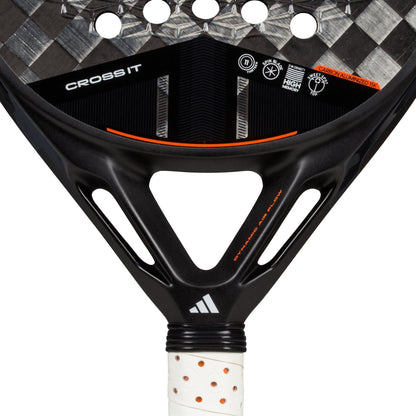 Close-up of the adidas Cross It 3.4 Padel Racket featuring a Carbon 15K face with black and silver carbon texture, orange accents, "CROSS IT" on the surface, and a white grip—ideal for aggressive players.