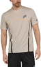 A man wears a Bullpadel Cabore Men's Padel T-Shirt in Peanut with Quickerdry tech and black graphics, paired with black shorts, standing with arms relaxed at his sides.