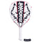 The Babolat Technical Vertuo Juan Lebrón Padel Racket features a white design with black and red accents, circular holes, a black Babolat logo on the face, a white grip-wrapped handle, and an attached black wrist strap.