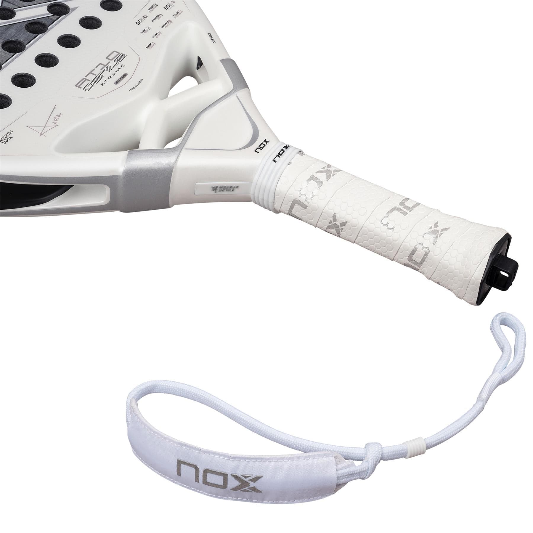 Close-up of the handle of the NOX AT10 Genius Attack 12K Alum Extrem By Agustín Tapia 2026 padel racket, showing a textured grip and a detachable wrist strap with "nox" in gray, laid separately below for optimal power play.