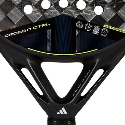 Close-up of the adidas ADIDAS Cross It CTRL 3.4 Padel Racket with a Carbon 15K face, showing "CROSS IT CTRL" and "Dynamic Air Flow" in white and green on its carbon finish, plus an adidas logo by the handle.