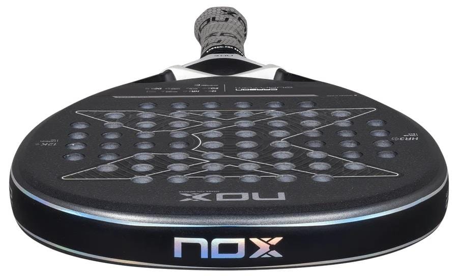 A close-up of the NOX Luxury Quantum 12K Carbon 2025 Padel Racket, showing its perforated black surface and NOX logo near the handle, crafted with 12K carbon fiber for superior performance.