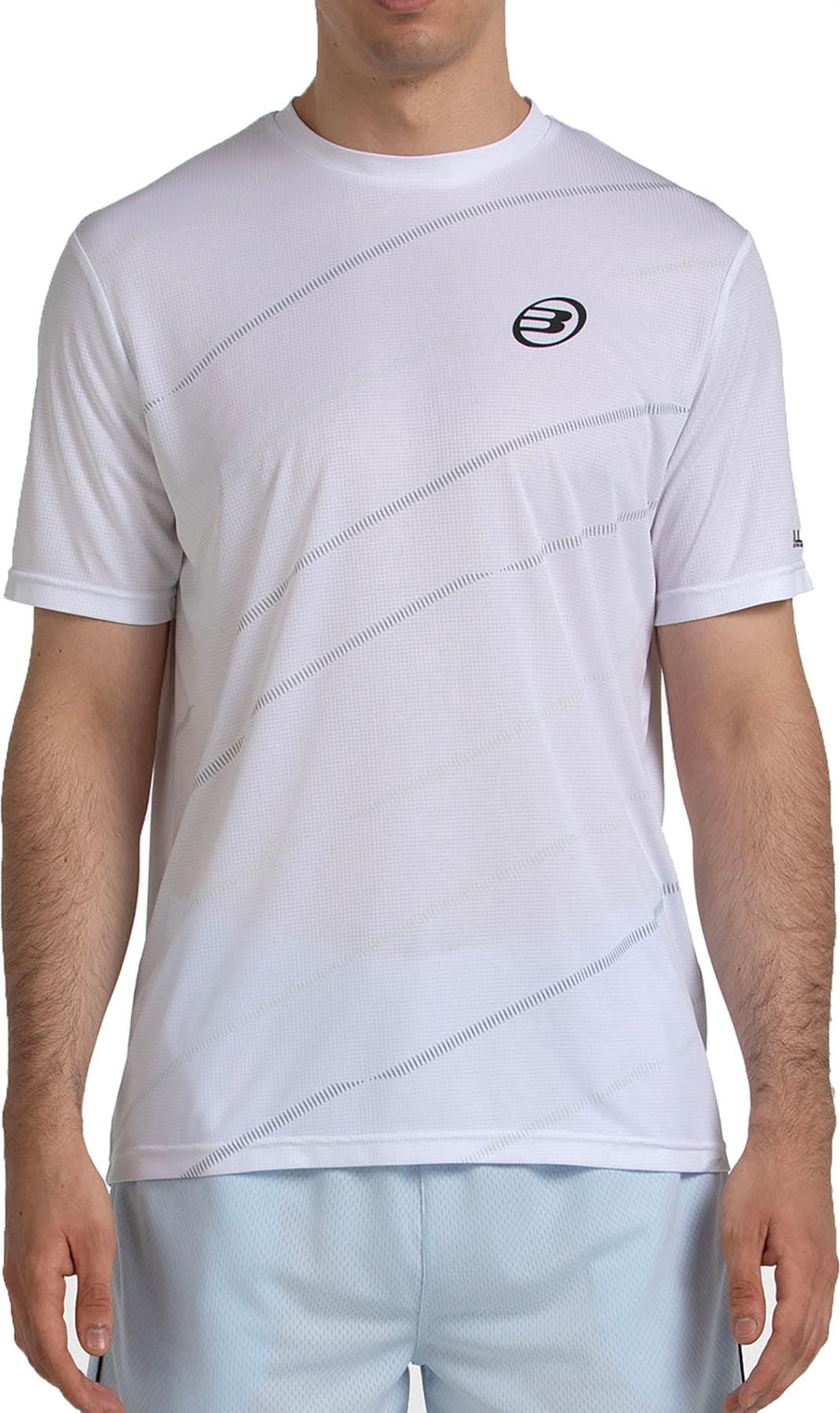 A man wears the Bullpadel Casinas Men's Padel T-Shirt in white, featuring subtle diagonal line patterns, a small black Bullpadel logo, and QuickerDry technology. He pairs it with light blue shorts; his face is not visible.