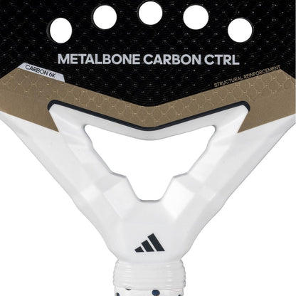 Close-up of the adidas Metalbone Carbon CTRL 3.4 padel racket for advanced players, labeled "METALBONE CARBON CTRL" with "CARBON 6K," "STRUCTURAL REINFORCEMENT," round holes, and the adidas logo near the handle.
