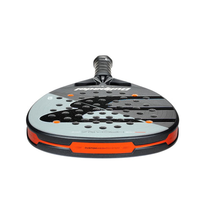 A close-up of the Bullpadel HACK 04 Comfort 2026 Padel Racket by Bullpadel, showing its black, gray, and orange design with multiple holes on the face and a textured grip handle for power and control.