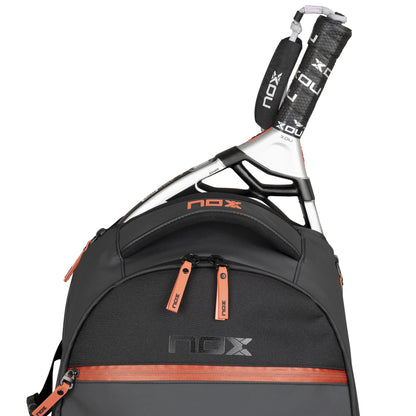 The NOX Luxury Open Series Padel Backpack - Black / Red features air ventilation, red zipper accents, and holds a NOX paddle racket with the NOX logo on both the bag and racket handle cover.