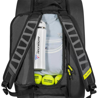 A partially unzipped black Tecnifibre Reform Padel Racket Bag reveals a white Tecnifibre water bottle, a light blue shirt, and three yellow padel balls—perfect for racket protection and reliability as a waterproof padel bag.